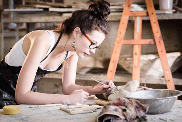 young artist moulding raw clay in art studio